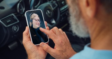 
						  Mann sitzt im Mercedes-Benz Fahrzeug und f�hrt ein Videogespr�ch mit einer Beraterin �ber sein Smartphone.
						  
