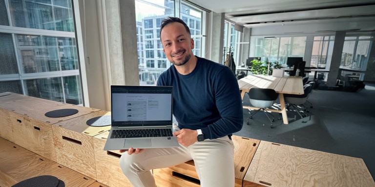 
				Mercedes-Benz Members Mitarbeiter Christian Panagiotidis an seinem Arbeitsplatz, in seiner Hand hlt er einen Laptop, auf dem der Fahrzeugpool der Website geffnet ist.
				
