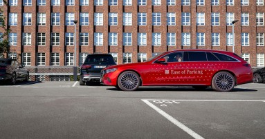 
						  Ein rotes Mercedes-Benz Fahrzeug mit der Aufschrift „Ease of Parking“ steht neben einer Parklcke auf einem Parkdeck.
						  