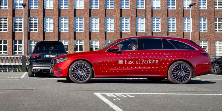 
				Ein rotes Mercedes-Benz Fahrzeug mit der Aufschrift „Ease of Parking“ steht neben einer Parklcke auf einem Parkdeck.
				