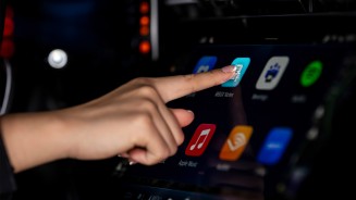 
Eine Hand bedient ber das Zentraldisplay verschiedene Apps.
