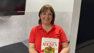 
Funda Wollny steht in ihrer K�che und h�lt ein Kochbuch in der Hand.
