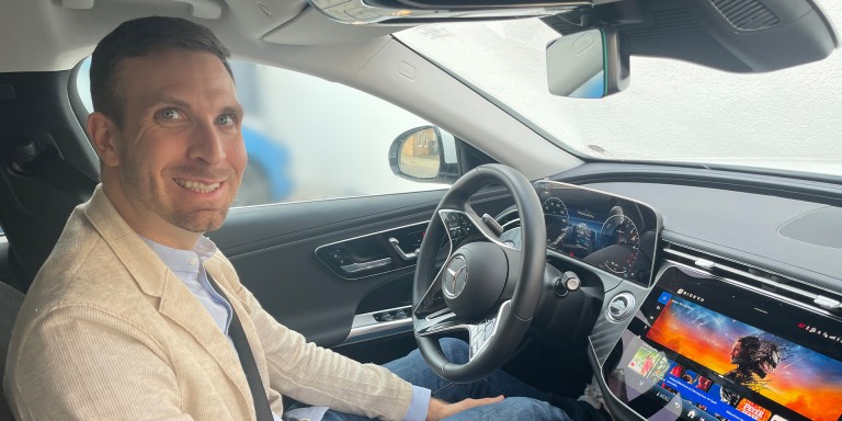 
				Produktmanager Christoph Nolting sitzt in einem Mercedes-Benz, das Zentraldisplay zeigt die Filmbibliothek von RIDEVU.
				
