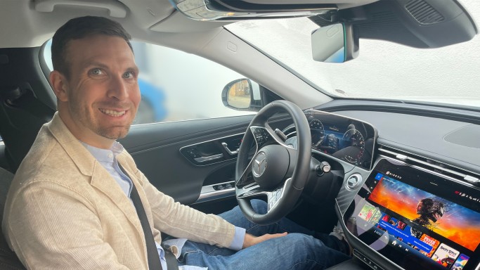 
				Produktmanager Christoph Nolting sitzt in einem Mercedes-Benz, das Zentraldisplay zeigt die Filmbibliothek von RIDEVU.
				