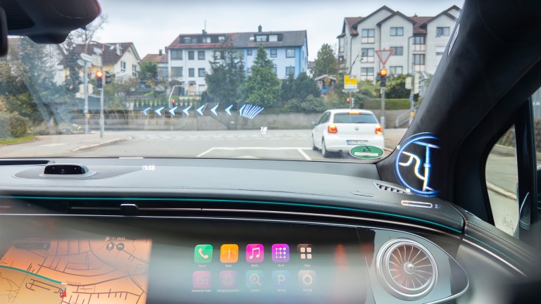 
			Blick durch eine AR-Brille vom Beifahrersitz auf die Strae, auf der Navigationshinweise ins Sichtfeld projiziert werden.
		
