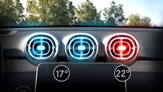 
Drei L�ftungsd�sen eines Mercedes-Benz Fahrzeugs unterhalb der Windschutzscheibe, �ber denen ein blauer Himmel und Baumkronen zu sehen sind.
