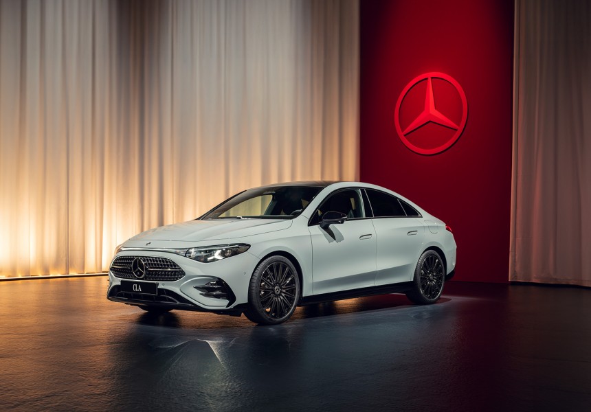 
			  	Wei�er Mercedes-Benz CLA in seitlicher Frontansicht vor beleuchtetem Vorhang und gro�em roten Mercedes-Stern an der Wand.
			  