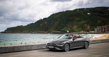 
						  Ein Mercedes-Benz CLE Cabriolet in graphitgrau magno mit AMG-Line steht vor einem Badestrand an einer Meereskste.
						  