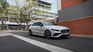 
Eine weie Mercedes-Benz A-Klasse Kompaktlimousine fhrt auf der Strae. Im Hintergrund eine Gebudefassade.
