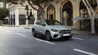 
Ein weier GLA parkt in einer Einfahrt vor einem Haus. Rechts grner Rasen und ein Baum ohne Bltter.
