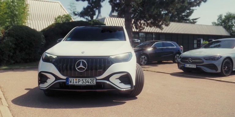 
				Frontalansicht eines weien EQE SUV mit eingeschlagenen Vorderrdern, der gerade rckwrts auf einem Parkplatz eingeparkt wird. Im Hintergrund stehen zwei weitere Mercedes-Benz Fahrzeuge.
				