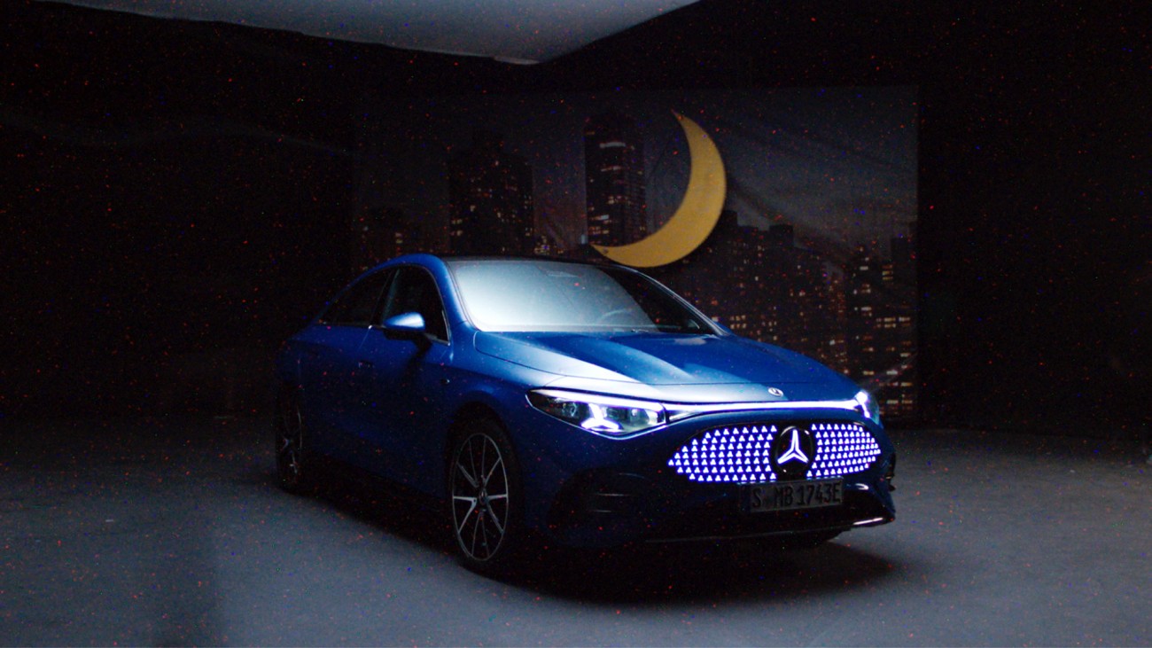 
			Ein blauer CLA mit EQ Technologie parkt vor einer dunklen Leinwand, auf der eine Gro�stadt-Skyline und ein gro�er gelber Mond abgebildet sind.
		