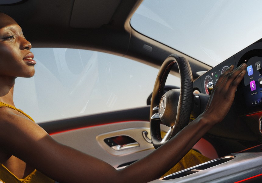 
			  	Eine Frau sitzt auf dem Fahrersitz eines CLA und bedient mit der rechten Hand das Zentraldisplay des MBUX Systems. Auf dem Touchscreen sind verschiedene App-Symbole zu sehen.
			  
