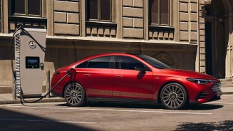 
Ein CLA in Lack MANUFAKTUR patagonienrot metallic steht seitlich geparkt an einer �ffentlichen Lades�ule vor einer historischen Geb�udefassade.
