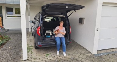 
						  Mercedes-Benz Mitarbeiterin Julia Lbbehusen steht vor ihrem EQT in Noseanblau.
						  