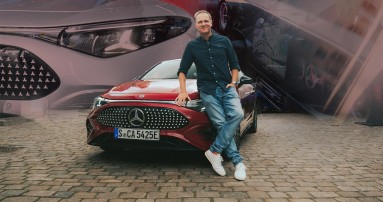 
					  Matthias Malmedie lehnt an der Motorhaube eines roten CLA mit EQ Technologie und blickt lchelnd in die Kamera.
					  