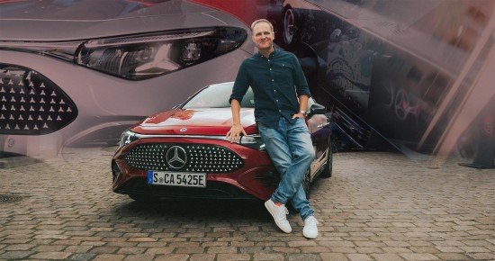 
					  Matthias Malmedie lehnt an der Motorhaube eines roten CLA mit EQ Technologie und blickt l�chelnd in die Kamera.
					  