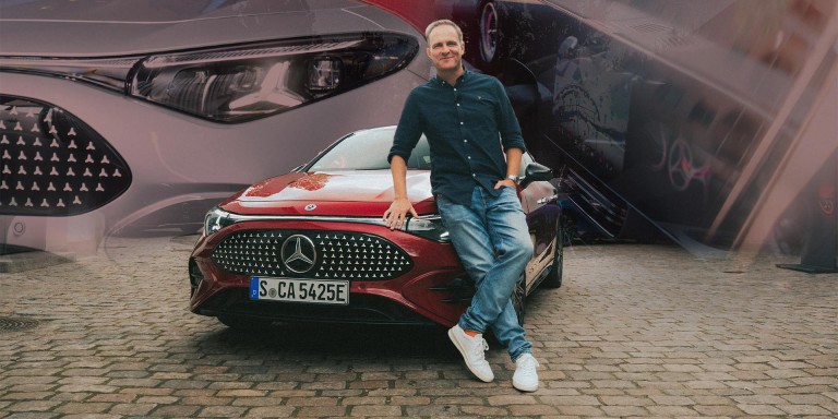 
				Matthias Malmedie lehnt an der Motorhaube eines roten CLA mit EQ Technologie und blickt l�chelnd in die Kamera.
				