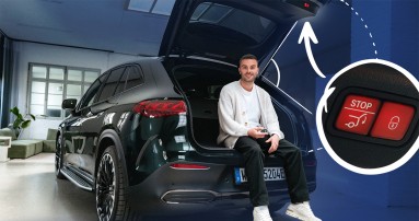
						  Produktmanager Christopher Hartung sitzt im geffneten Kofferraum eines Mercedes-Benz, hlt den Fahrzeugschlssel in der Hand und blickt in die Kamera. Rechts im Bild sind in einem kleinen Kreis die Stopptaste/Schlietaste und rechts daneben eine Taste mit einem Schloss darauf vergrert abgebildet.
						  