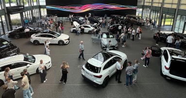 
						  Mehrere Mercedes-Benz Fahrzeuge stehen in einer Halle. Mehrere Besucherinnen und Besucher des Familientags Bremen begutachten die ausgestellten Fahrzeuge.
						  