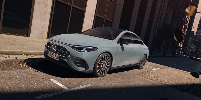 
				Der CLA Hybrid in aquamint in einer Aufnahme von schrg vorne auf dem sonnigen Parkplatz einer Strae stehend.
				