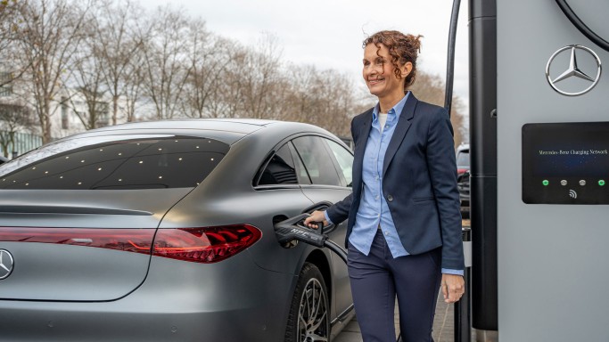
				Eine Frau in dunkelblauer Office-Kleidung l�dt ihren vollelektrischen Mercedes-Benz an der Lades�ule eines Mercedes-Benz Charging Hubs auf.
				