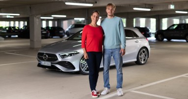 
						  Susanne Gutmann (links) und ihr Sohn Leon stehen in einem Parkhaus vor einer silbernen A-Klasse. Im Hintergrund sind weitere Fahrzeuge zu sehen.
						  