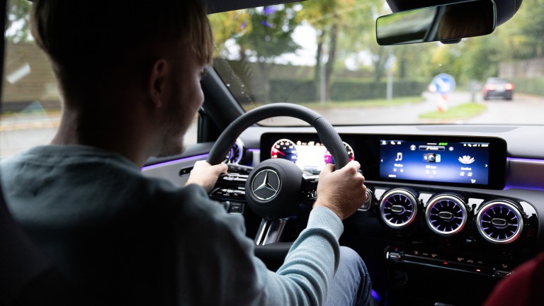 
			Seitliche R�ckansicht von Leon Gutmann am Steuer einer Mercedes-Benz A-Klasse. Beide H�nde umfassen das Lenkrad, der Blick ist auf die Stra�e gerichtet.
		