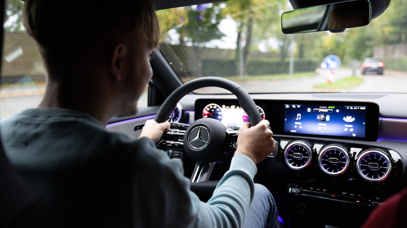 
			Seitliche R�ckansicht von Leon Gutmann am Steuer einer Mercedes-Benz A-Klasse. Beide H�nde umfassen das Lenkrad, der Blick ist auf die Stra�e gerichtet.
		