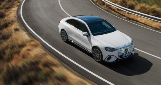 
					  Die neue elektrische Mercedes-Benz C-Klasse in MANUFAKTUR opalithwei� metallic bright f�hrt durch eine lang gezogene Linkskurve auf einer Landstra�e. Sichtbar sind die flie�ende coup�hafte Silhouette und das schwarze Panoramadach. Links und rechts der Fahrbahn ist eine trockene, h�gelige Landschaft zu sehen.
					  