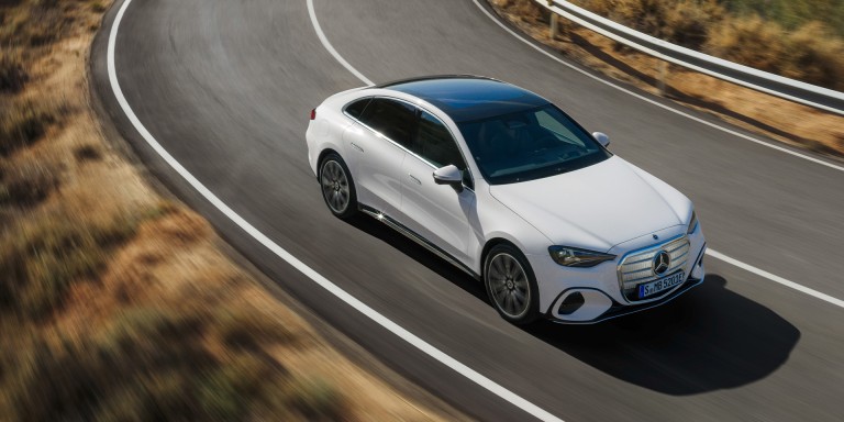
				Die neue elektrische Mercedes-Benz C-Klasse in MANUFAKTUR opalithwei� metallic bright f�hrt durch eine lang gezogene Linkskurve auf einer Landstra�e. Sichtbar sind die flie�ende coup�hafte Silhouette und das schwarze Panoramadach. Links und rechts der Fahrbahn ist eine trockene, h�gelige Landschaft zu sehen.
				