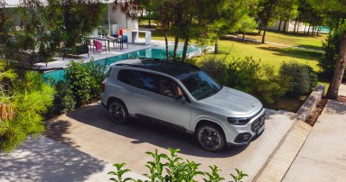 
					  Ein Mercedes-Benz GLB in Hightechsilber metallic steht r�ckw�rts eingeparkt in einer Einfahrt vor einem Garten mit Pool, aufgenommen aus schr�ger Vogelperspektive. Auf der Fahrerseite und hinter dem Fahrzeug befindet sich eine Hecke.
					  