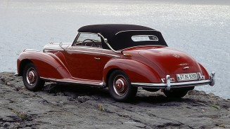 
Historisches Mercedes-Benz 300 S Cabriolet A (Baureihe W 188 I) aus dem Jahr 1952 in dunkelroter Lackierung, von schr�g hinten fotografiert, mit geschlossenem Stoffverdeck vor einem Gew�sser.
