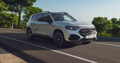 
					  Vorderansicht des elektrischen Mercedes-Benz GLB in Hightechsilber, der auf einer Landstra�e f�hrt. Entlang der Stra�e sind gr�ne B�ume und Vegetation zu sehen, dar�ber ein klarer Himmel.
					  