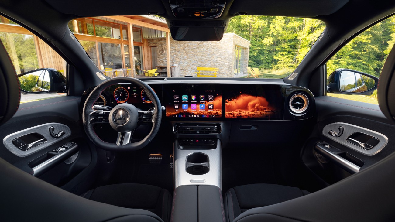 
			Blick vom R�cksitz auf das Cockpit des neuen GLA von Mercedes-Benz und den optionalen MBUX Superscreen, auf dem eine orange-rote Visualisierung zu sehen ist. Durch die Windschutzscheibe ist zu erkennen, dass das Fahrzeug vor einem modernen Haus im Wald steht.
		