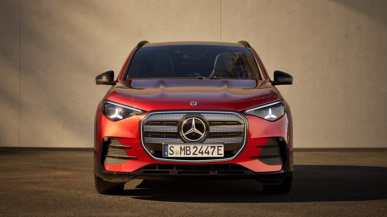
			Frontalansicht des neuen GLA von Mercedes-Benz in MANUFAKTUR patagonienrot metallic vor einem betonfarbenen Hintergrund.
		