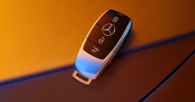 
					  Ein moderner Autoschl�ssel von Mercedes-Benz mit drei Tasten und dem Herstellerlogo liegt auf einer zweifarbigen Oberfl�che. Der Schl�ssel ist aus Metall und Kunststoff gefertigt.
					  