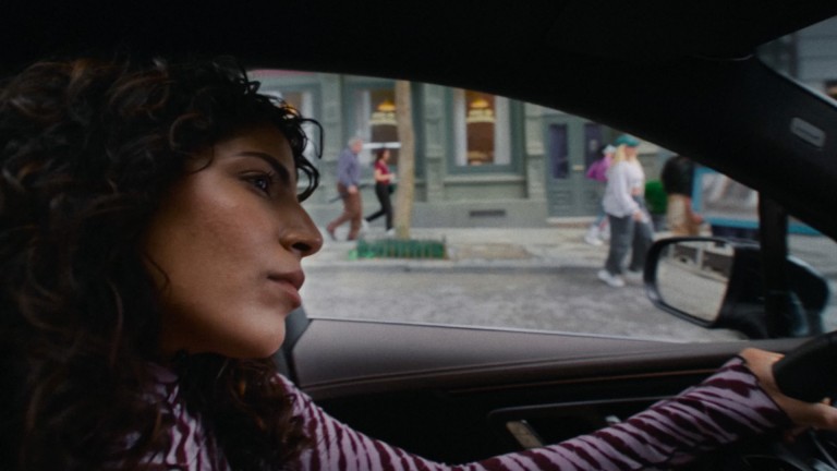 
			Eine Frau sitzt am Steuer eines Mercedes-Benz. Im Hintergrund ist eine belebte Stadtstra�e mit Fu�g�ngern zu sehen.
		