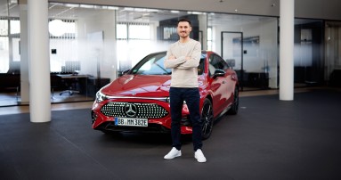 
					  Felix B�llmann, Customer Onboarding f�r Digitale Extras bei Mercedes-Benz, steht l�chelnd und mit verschr�nkten Armen vor einem roten, elektrischen Mercedes-Benz CLA.
					  