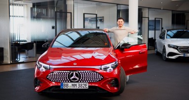 
					  Felix B�llmann, Customer Onboarding f�r Digitale Extras bei Mercedes-Benz, steht l�chelnd neben der ge�ffneten Fahrert�r eines elektrischen Mercedes-Benz CLA in MANUFAKTUR patagonienrot metallic.
					  