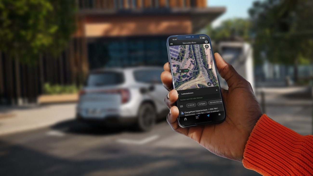 
			Im Vordergrund h�lt eine Hand ein Smartphone, auf dem eine Kartenansicht der Umgebung zu sehen ist, auf dem die Navigation mit Electric Intelligence m�gliche Ladestationen anzeigt. Im Hintergrund ist unscharf ein Mercedes-Benz Fahrzeug an einer Lades�ule zu sehen.
		