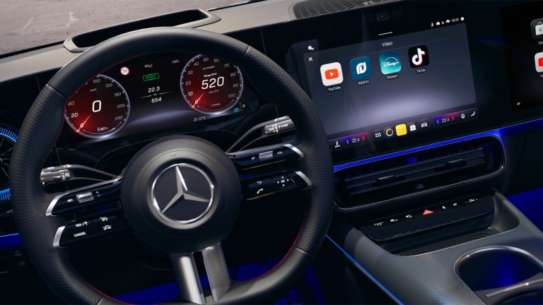 
			Blick auf das Steuer eines Mercedes-Benz Fahrzeugs und den Zentralbildschirm, auf dem die Apps YouTube, RIDEVU, Disney+ und TikTok zu erkennen sind.
		
