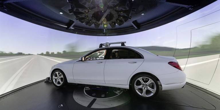 
				Ein wei�er Mercedes-Benz steht im Handling-Simulator im Mercedes-Benz Technology Center Sindelfingen. Um das Fahrzeug herum ist eine 360-Grad-Leinwand zu sehen, auf der eine Fahrbahn simuliert wird.
				