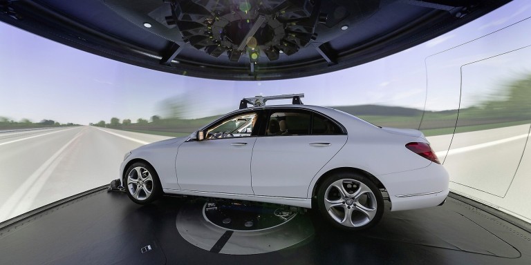 
				Ein wei�er Mercedes-Benz steht im Handling-Simulator im Mercedes-Benz Technology Center Sindelfingen. Um das Fahrzeug herum ist eine 360-Grad-Leinwand zu sehen, auf der eine Fahrbahn simuliert wird.
				
