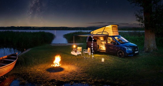 
					  Ein Mercedes-Benz Marco Polo in sodalithblau metallic steht an einem See in n�chtlicher Atmosph�re unter dem Sternenhimmel. Das Aufstelldach ist aufgestellt. Im Innenraum des MarcoPolo brennt orange-gelbes Licht.  Die Markise ist ge�ffnet und es h�ngt eine Lichterkette bis zum Boden. Unter der Markise  stehen zwei Campingst�hle an einem Campingtisch. Am linken Bildrand ist ein Ruderboot zu sehen, das am Seeufer liegt. Zwischen Boot und der Campingbestuhlung brennt eine Feuerschale.
					  
