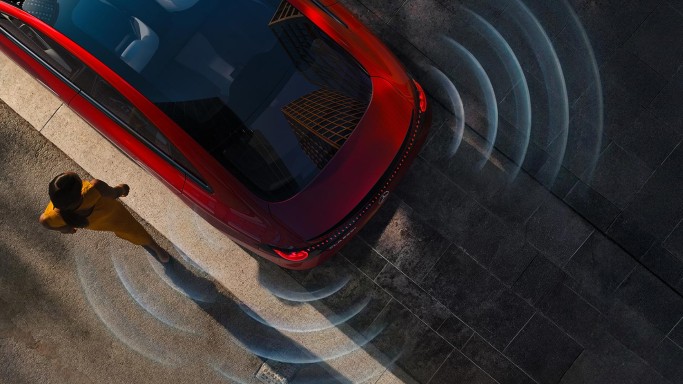 
				Blick von oben auf einen roten CLA von Mercedes-Benz, von dem Schallwellen ausgehen, die den akustischen Umfeldschutz darstellen. Links neben dem Fahrzeug l�uft eine Frau in einem gelben Kleid vorbei.
				
