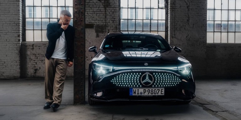 
				Christopher Hartung steht neben einem elektrischen CLA von Mercedes-Benz in nachtschwarz uni, dessen Frontscheinwerfer erleuchtet sind. Christopher h�lt beeindruckt seine rechte Hand vor den Mund und schaut zum Fahrzeug.
				