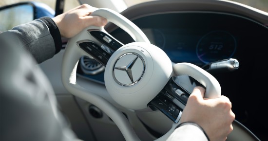 
					  Zwei H�nde halten das abgeflachte Steer-by-Wire-Lenkrad des Mercedes-Benz EQS. Im Hintergrund sind Ausschnitte des digitalen Fahrerdisplays und des Cockpits zu sehen.
					  