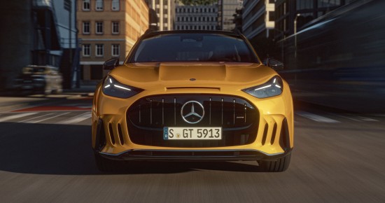 
					  Ein Mercedes-AMG GT SUV f�hrt mit eingeschaltetem Tagfahrlicht durch eine Stadtstra�e. Das Fahrzeug ist frontal zu sehen, mit gro�em Mercedes-Benz Stern im schwarzen K�hlergrill. Im Hintergrund sind mehrst�ckige Geb�ude unscharf zu erkennen.
					  