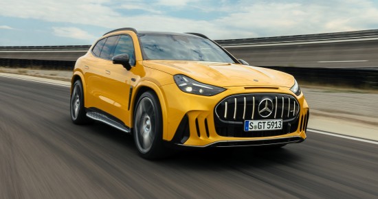 
					  Ein Mercedes-AMG GT SUV in MANUFAKTUR solarbeam metallic f�hrt auf einer asphaltierten Stra�e. Das Fahrzeug ist aus einer schr�gen Frontperspektive von links aufgenommen und nimmt einen gro�en Teil des Bildes ein. Zu sehen sind der schwarze K�hlergrill mit Mercedes-Benz-Emblem, die eingeschalteten Scheinwerfer und die seitliche Karosserie. Die Fahrbahn und die Leitplanken erscheinen durch die Bewegung verschwommen. Im Hintergrund ist ein leicht bew�lkter Himmel zu sehen.
					  